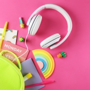 Hipster neon green textile backpack, surrounded with school supplies. Back to school concept. Lots of different stationery items on colorful background. Close up, copy space, flat lay, top view.