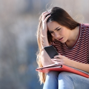 Worried student checking bad news on phone Worried student checking bad exam results